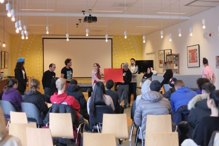 Twee jongeren presenteren iets aan een groep.