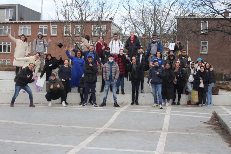 Groep van 30 mensen poseren in de buitenlucht.