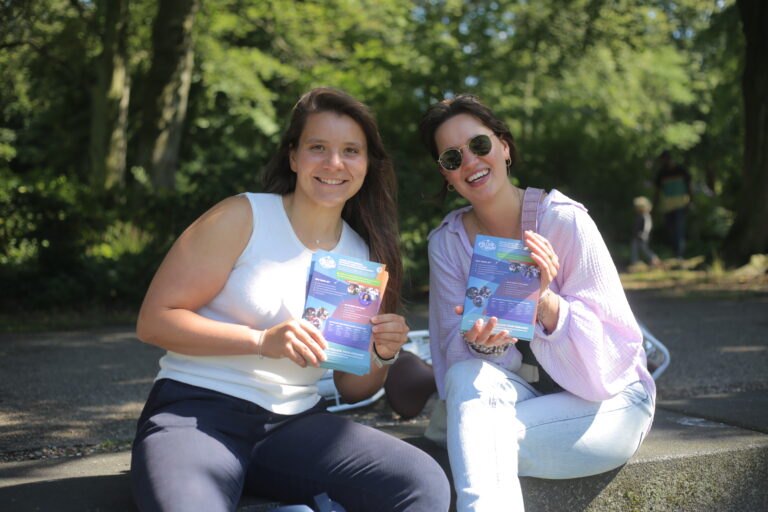 Twee meiden poseren met flyers van het Follow Your Dreams-programma in de hand.